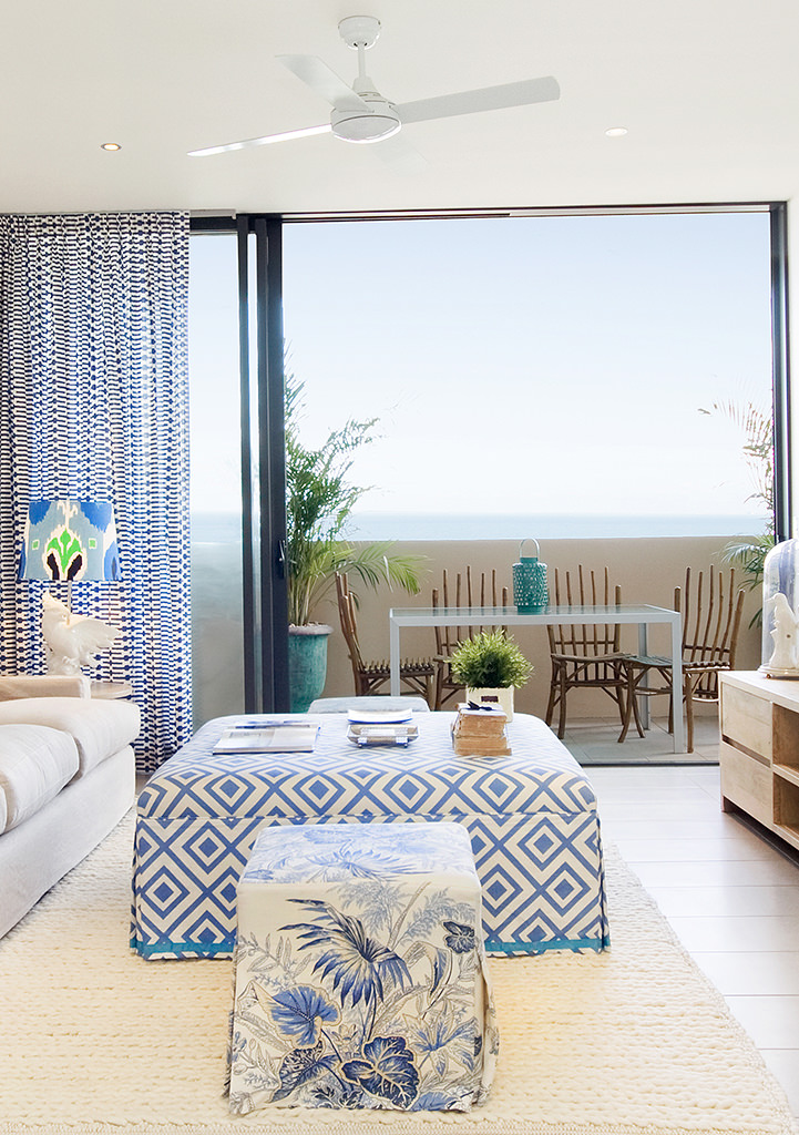 coastal living room with blue diamond upholstered ottoman sliding doors open to ocean view balcony