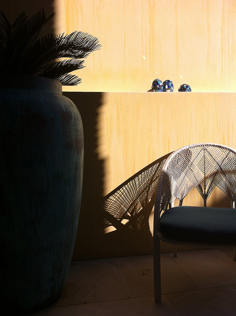 outdoor terrace with warm yellow wall rattan chair and ceramic vase at sunset