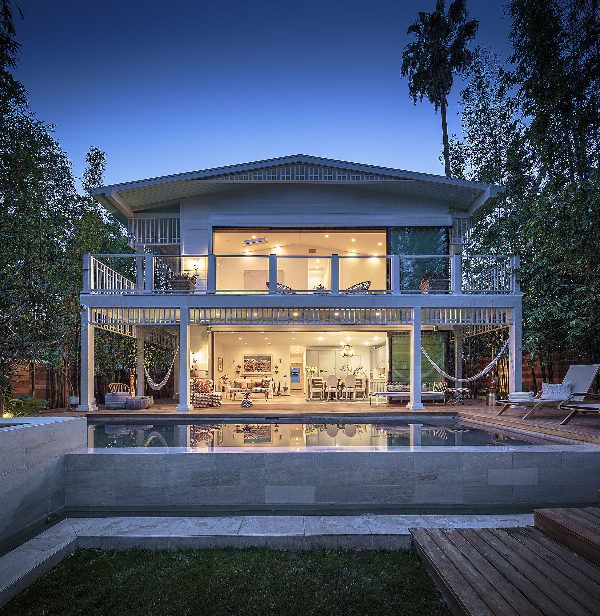 Hollywood Hills home exterior at dusk with wraparound verandah pool reflection and bamboo garden