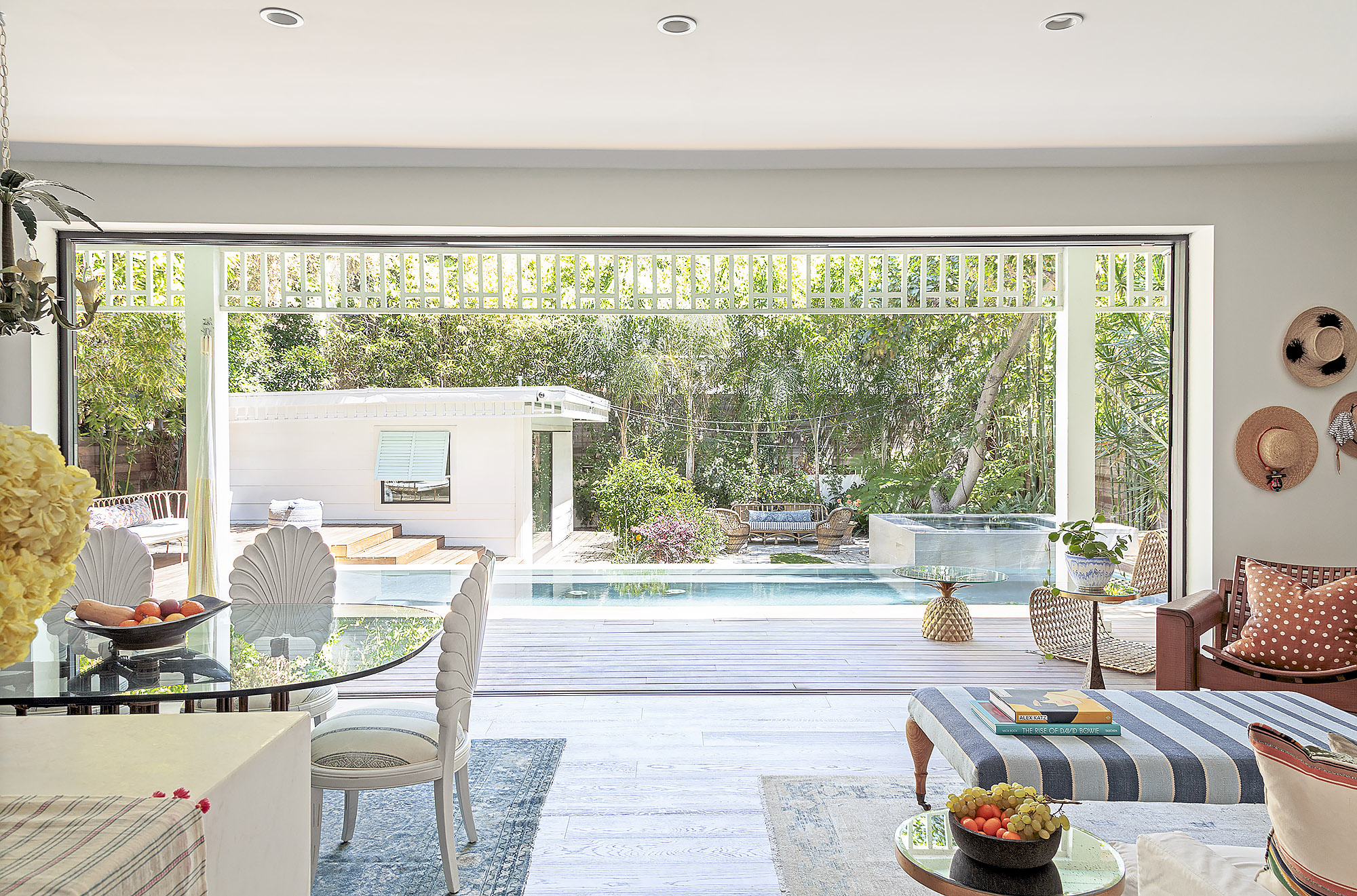 California indoor outdoor living room with bifold doors opening to pool view and garden