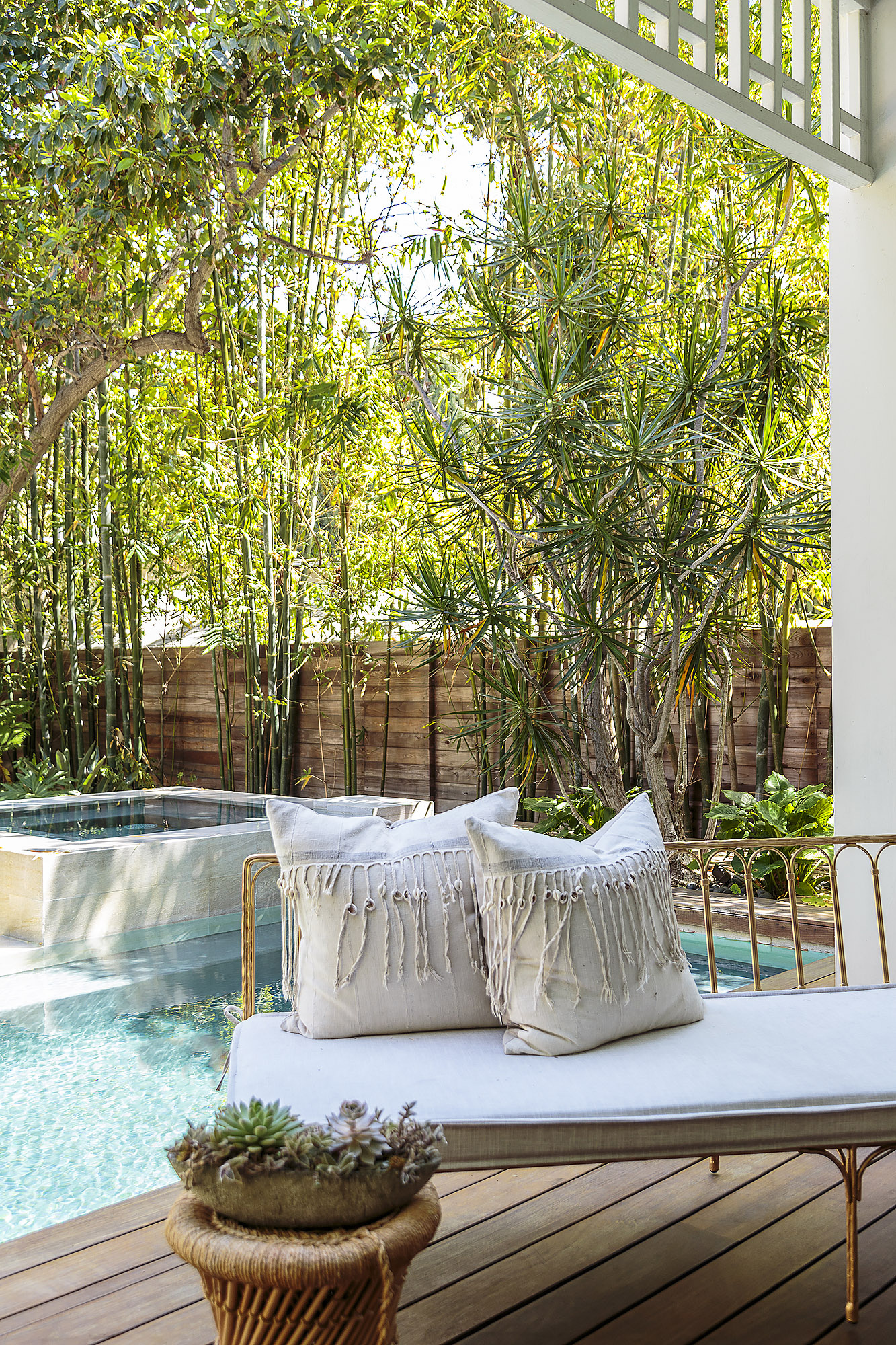 poolside gold daybed with macrame cushions surrounded by bamboo garden on timber deck