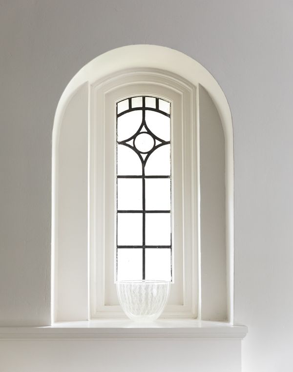 Elegant arched window with geometric leadlight and crystal vase