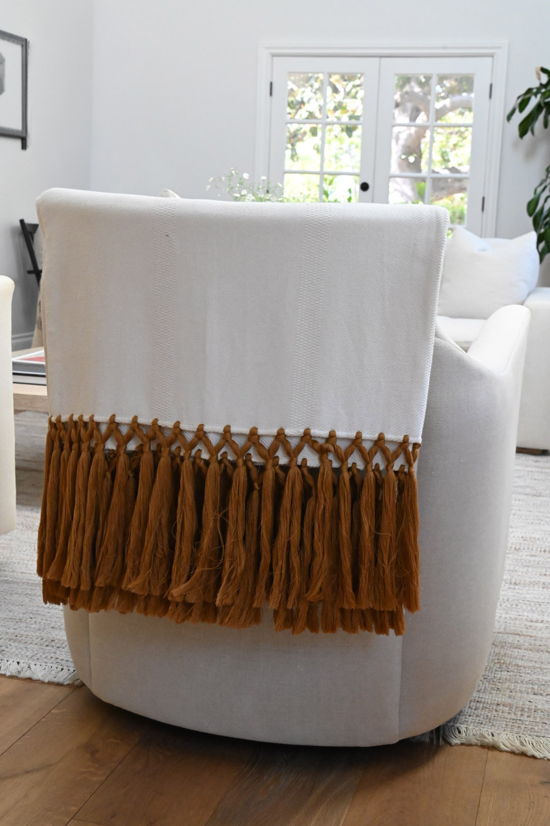 Living room white swivel chair cream throw caramel macrame tassel fringe jute rug french doors — Bronwyn Poole Interiors Living room white swivel chair cream throw caramel macrame tassel fringe jute rug french doors — Bronwyn Poole Interiors