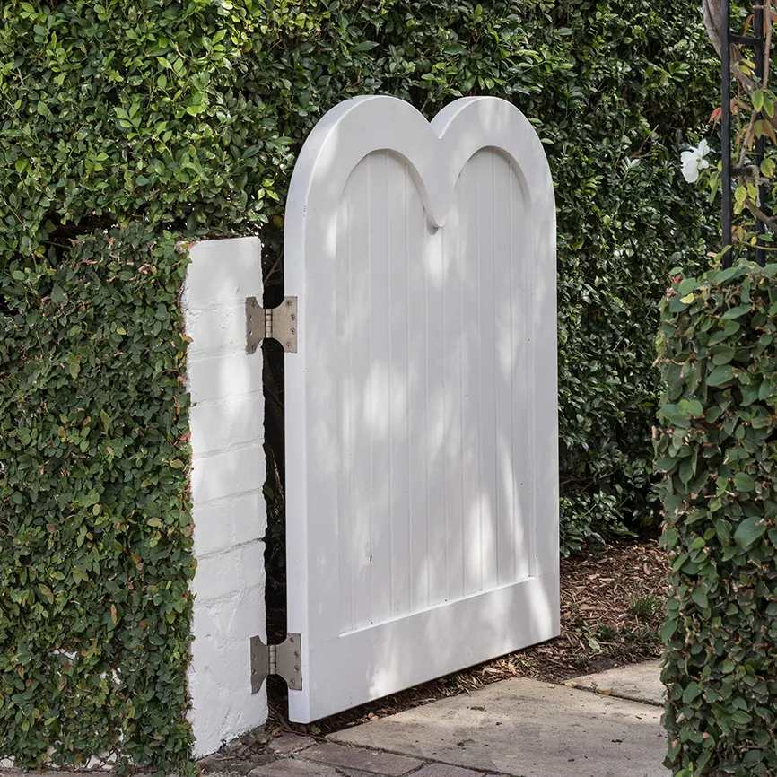 White arched garden gate with ivy hedge at Spruson Project by Touch Interiors