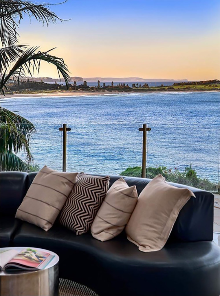beachfront terrace with leather sofa and ocean sunset view framed by palm fronds