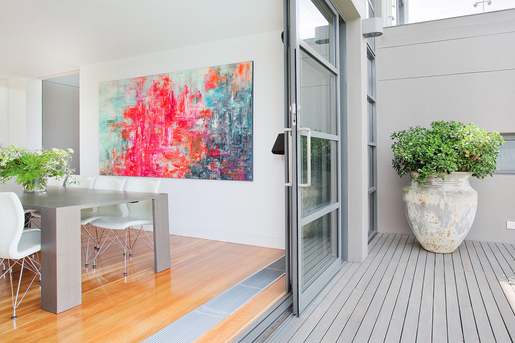 dining room to outdoor deck transition with abstract art bifold doors and timber floor