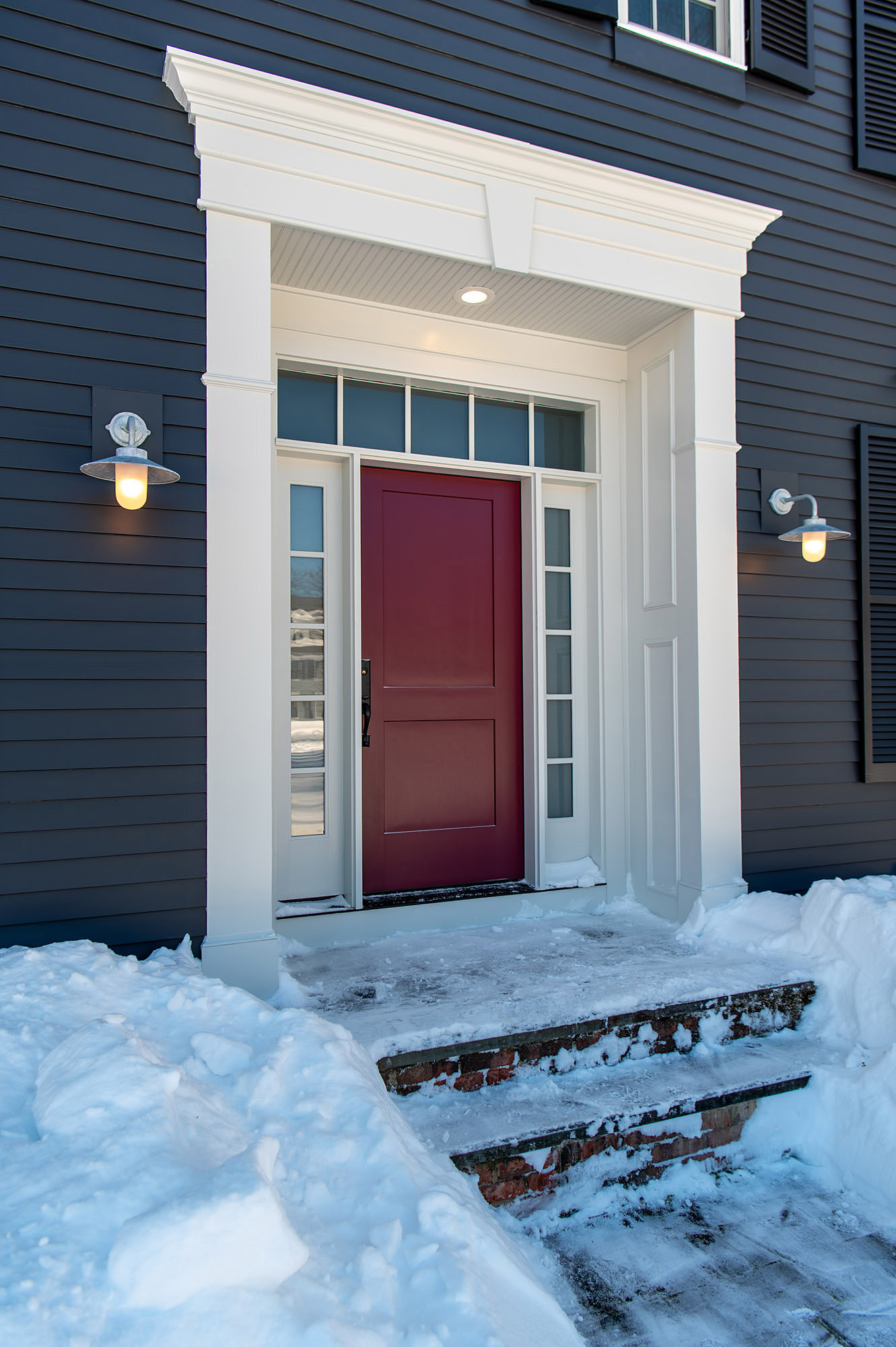 Front door detail burgundy shaker door white portico pediment galvanized barn sconces charcoal siding snow brick steps — Bronwyn Poole Interiors Front door detail burgundy shaker door white portico pediment galvanized barn sconces charcoal siding snow brick steps — Bronwyn Poole Interiors