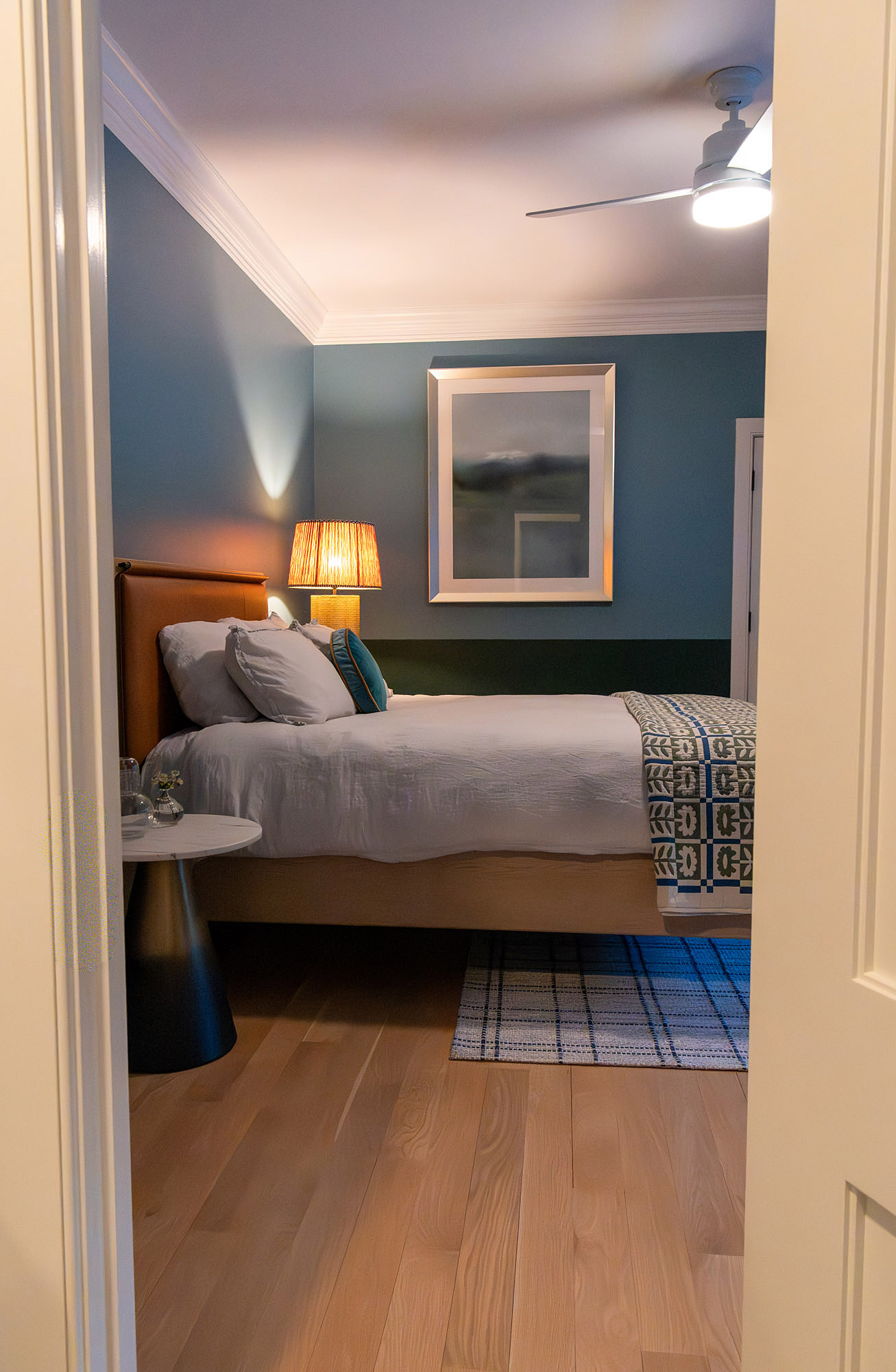 Jack jill bedroom doorway view teal walls orange leather headboard pleated shade lamp greek key coverlet plaid rug — Bronwyn Poole Interiors