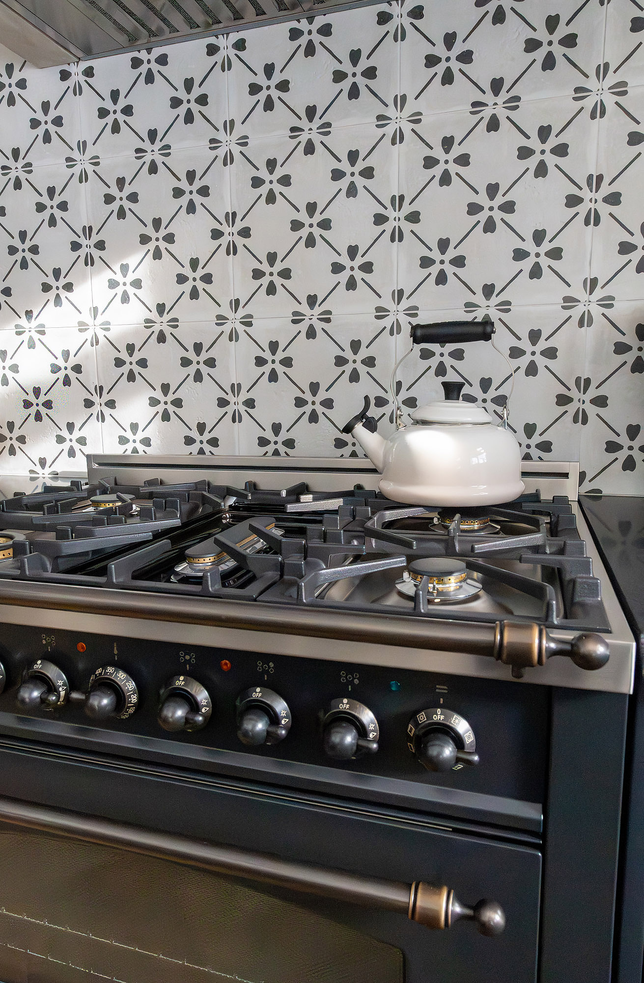 Kitchen stove detail bronze knobs cream kettle cast iron grates graphite floral tile — Bronwyn Poole Interiors