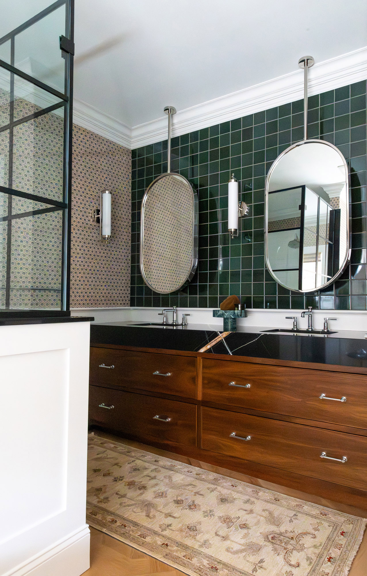 Primary bathroom wide view green heath tile walnut vanity dual oval mirrors iron shower screen floral rug — Bronwyn Poole Interiors