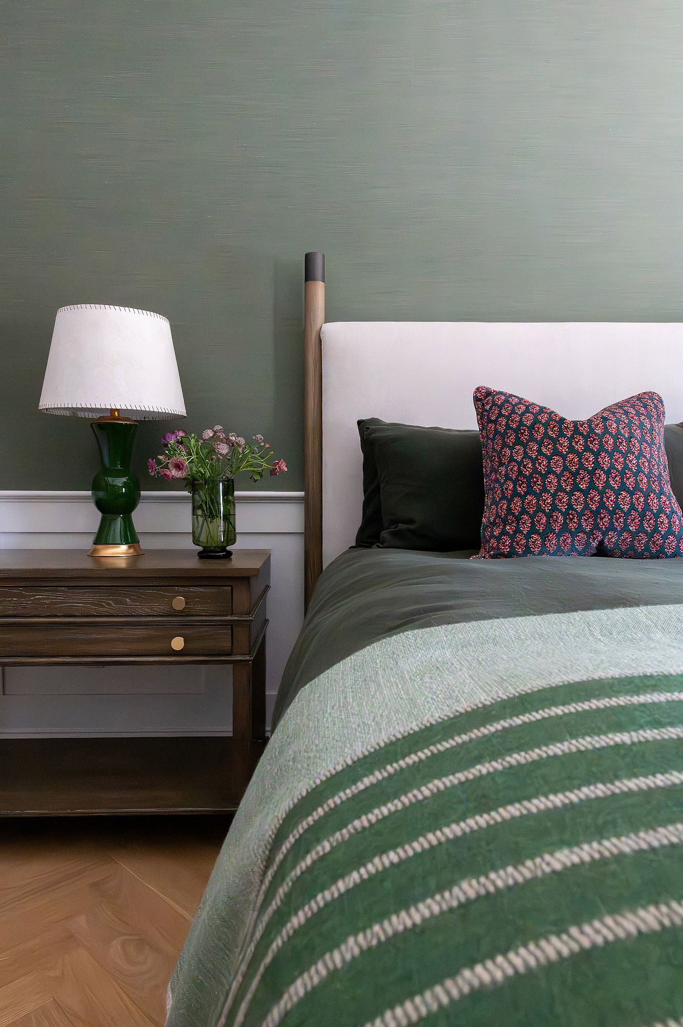 Primary bedroom bedside detail green glass lamp walnut nightstand block print pillow green striped throw linen headboard — Bronwyn Poole Interiors