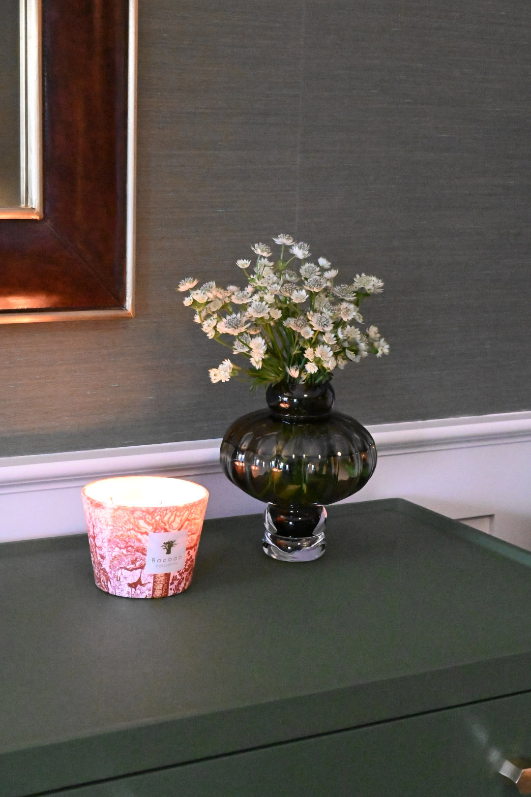 Primary bedroom vignette green lacquered dresser smoked glass vase astrantia baobab candle grasscloth wallpaper burlwood mirror — Bronwyn Poole Interiors
