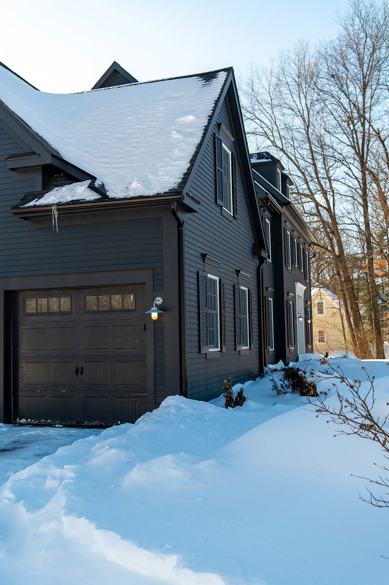 Side elevation charcoal siding garage door galvanized sconce snow covered roof bare trees — Bronwyn Poole Interiors Side elevation charcoal siding garage door galvanized sconce snow covered roof bare trees — Bronwyn Poole Interiors