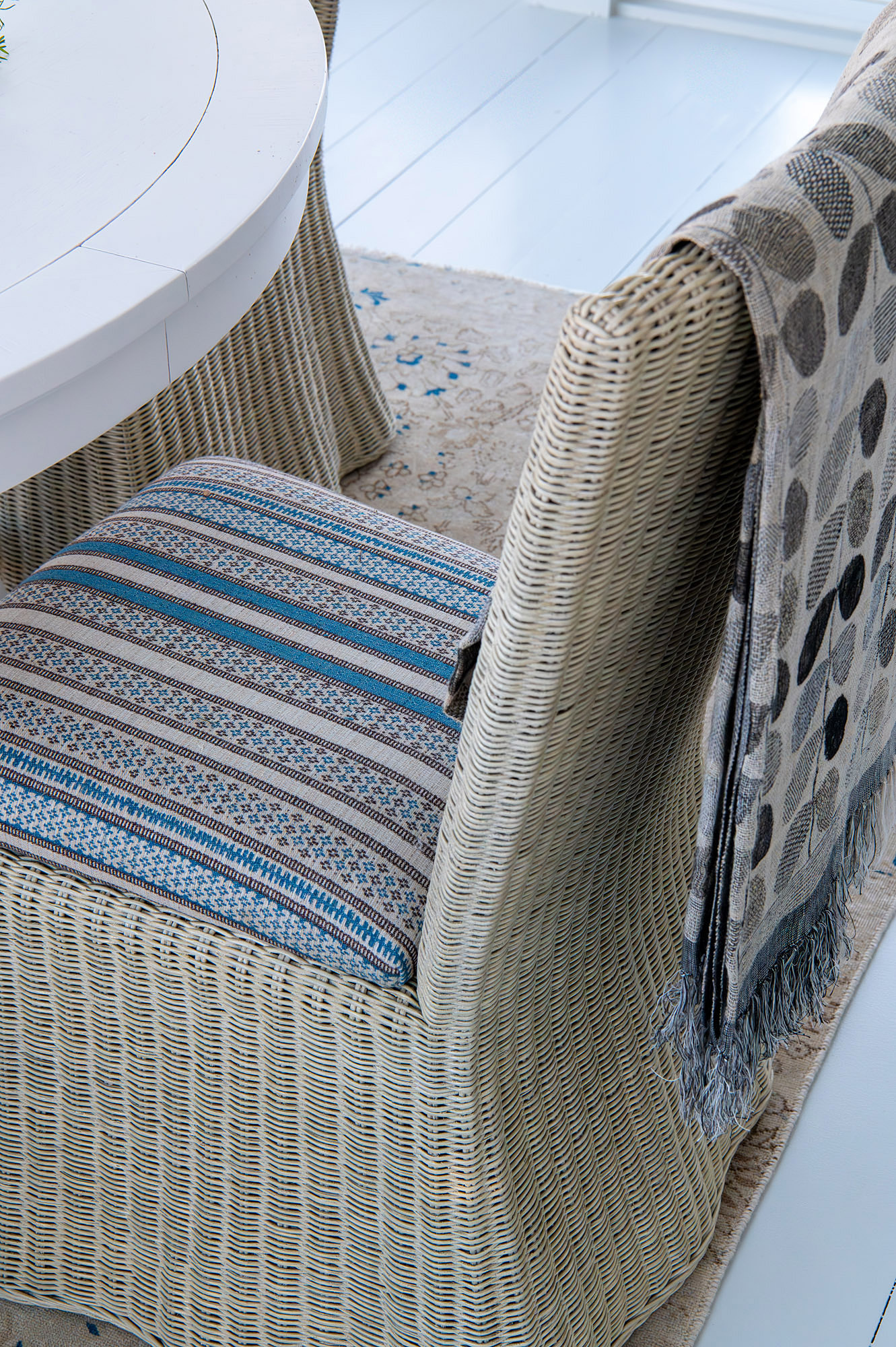 Sunroom detail natural wicker chair blue striped cushion grey spotted throw vintage rug white floor — Bronwyn Poole Interiors