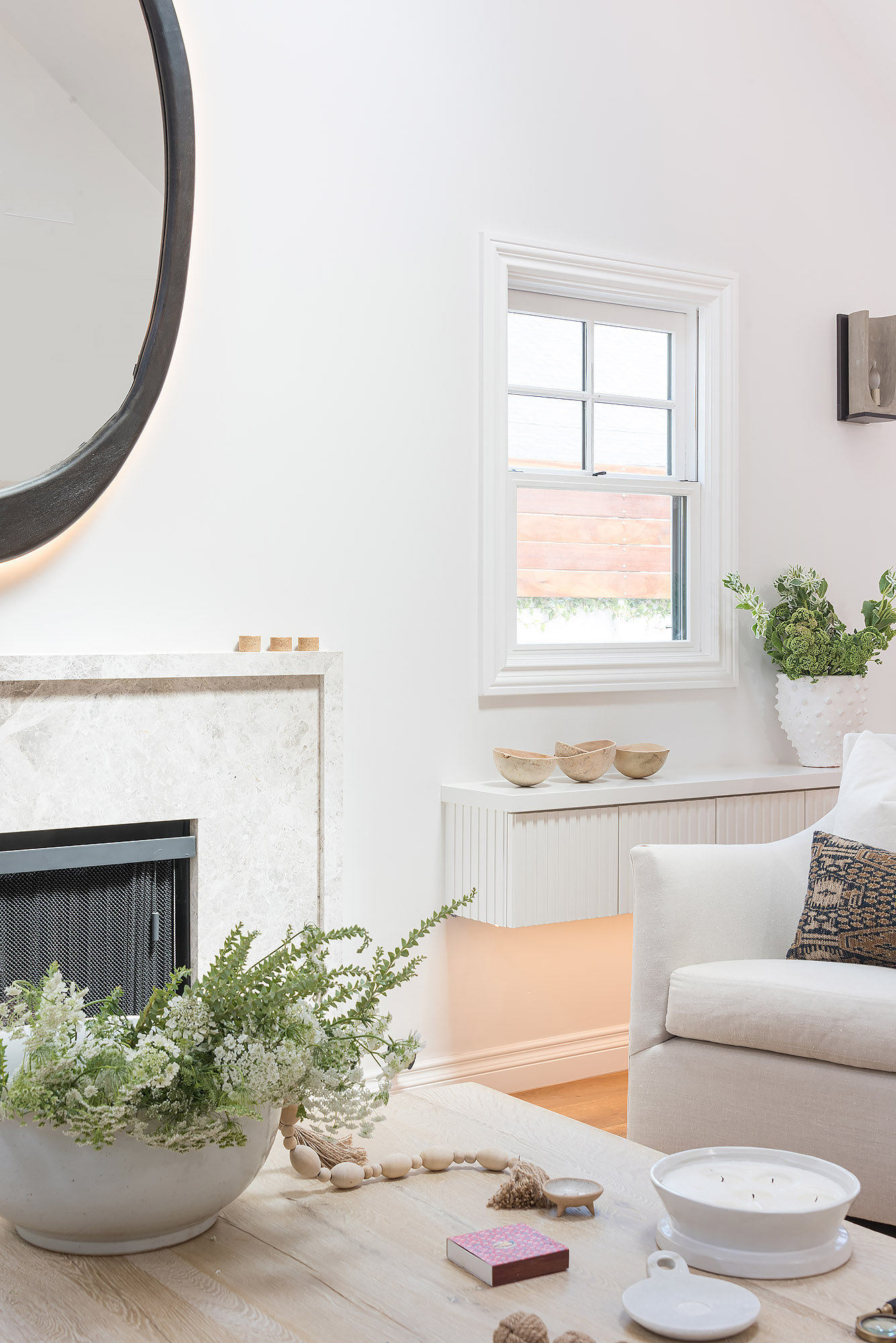 Living room detail marble fireplace round mirror wildflower arrangement wooden bowls — Bronwyn Poole Interiors Living room detail marble fireplace round mirror wildflower arrangement wooden bowls — Bronwyn Poole Interiors
