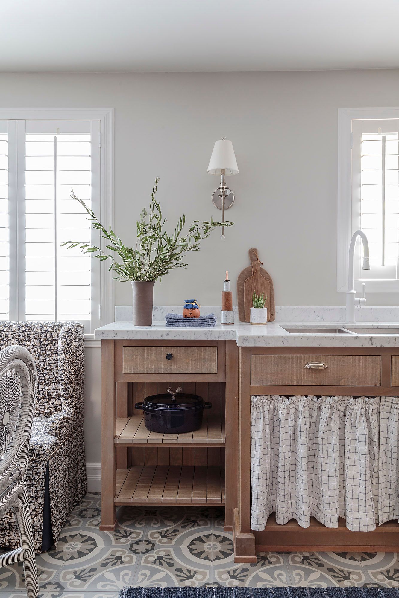 kitchen detail with oak cabinets marble counter linen curtain and plantation shutters filtering natural light